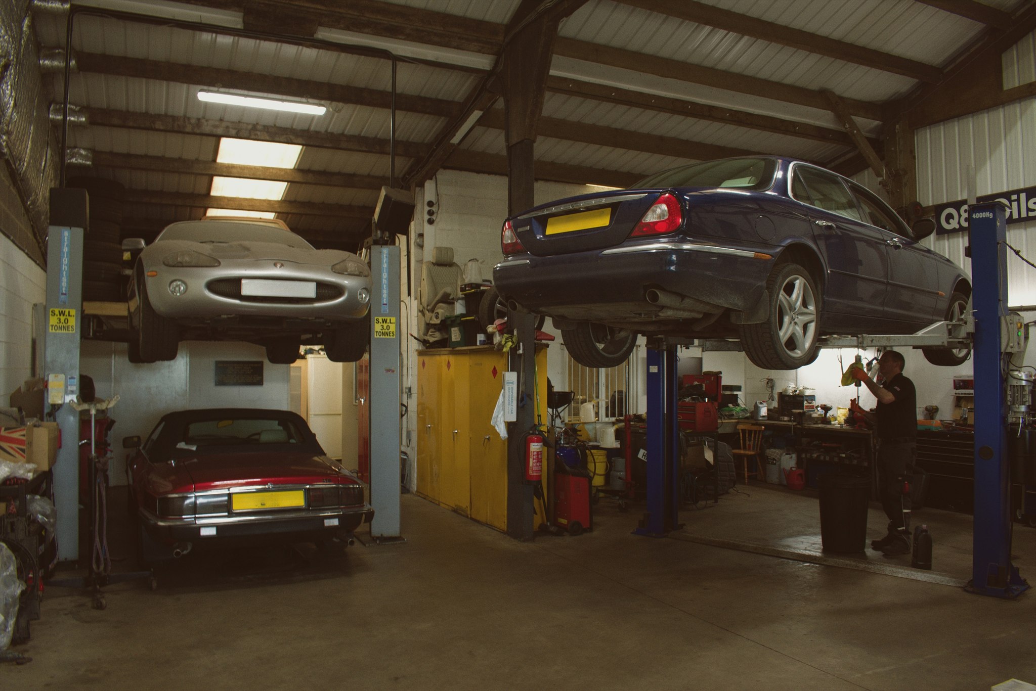 Active workshop bays with vehicles raised on two-post lifts